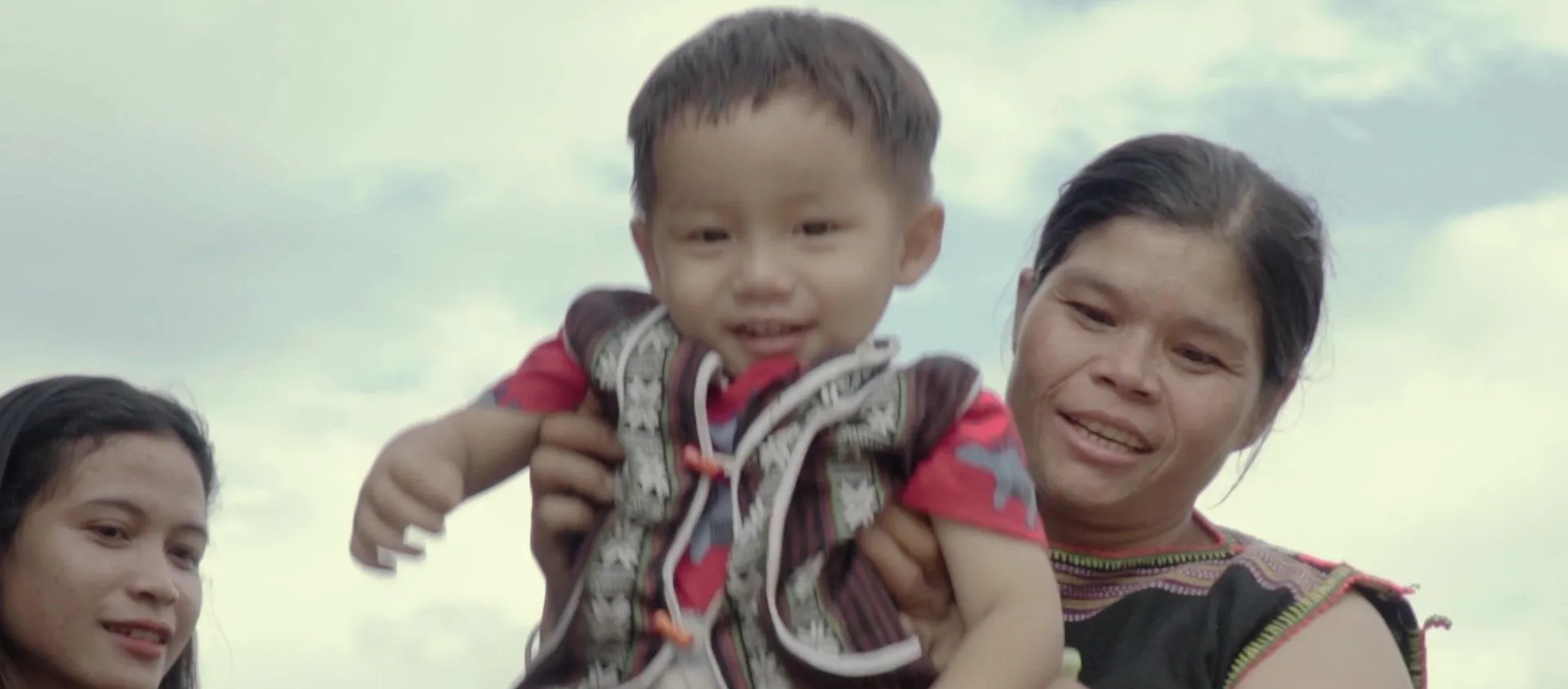 A child held up against the sky, from the documentary teaser