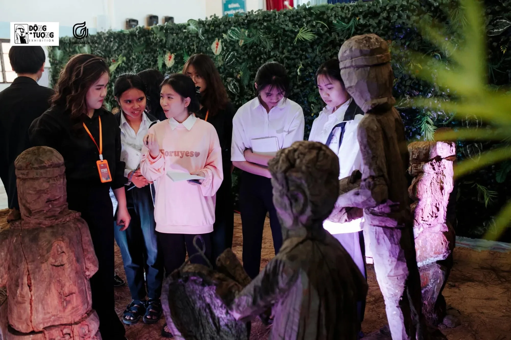 Students taking notes among wooden tomb house statues at Động Tượng, the exhibition by YUU Organization