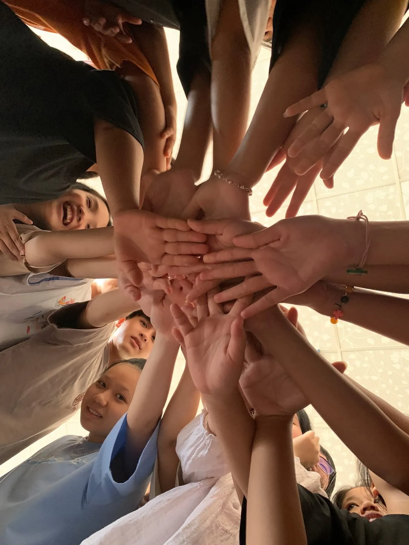Young people stacking their hands together in a circle, seen from below
