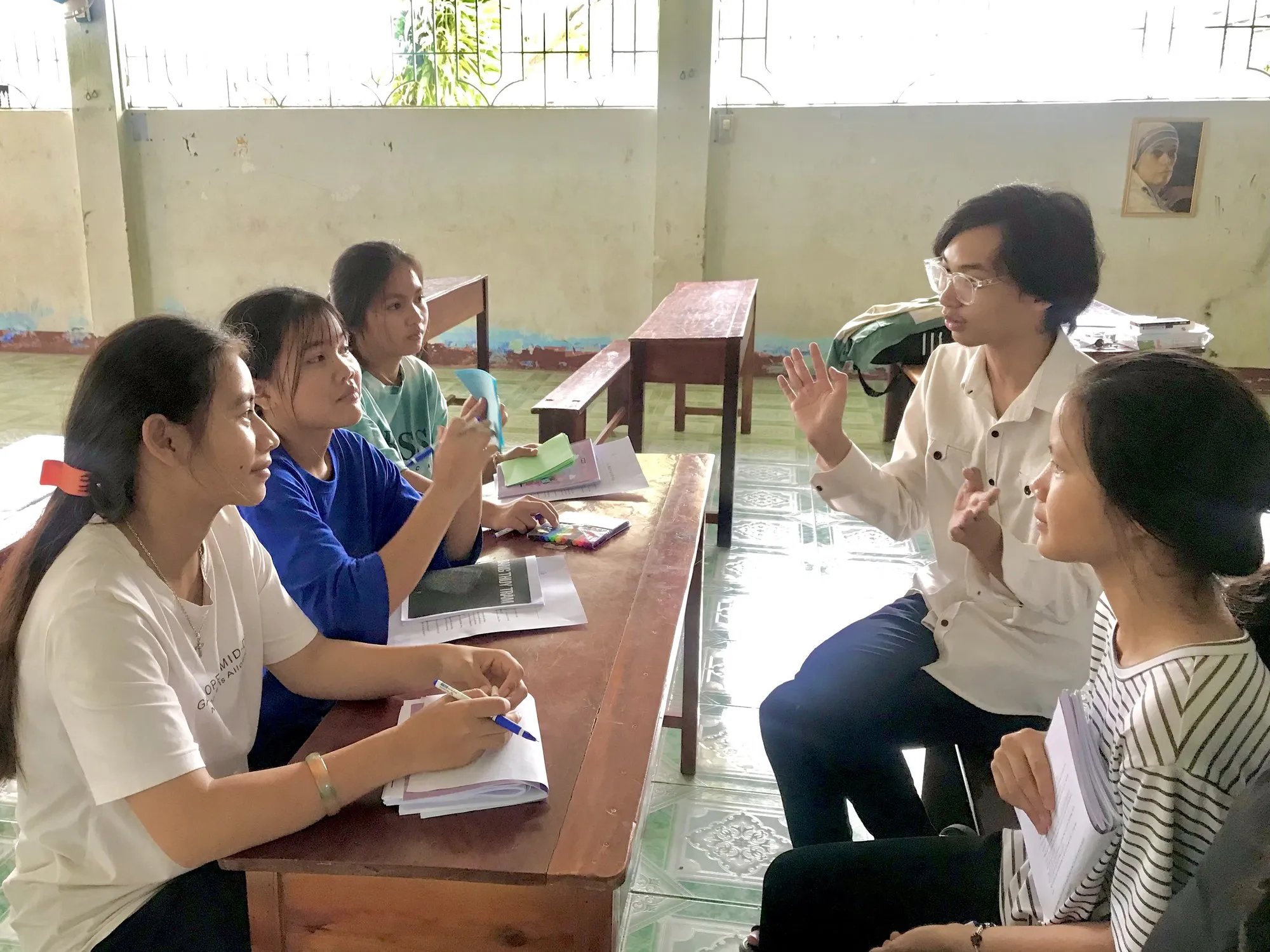 A facilitator talking with students around a classroom table