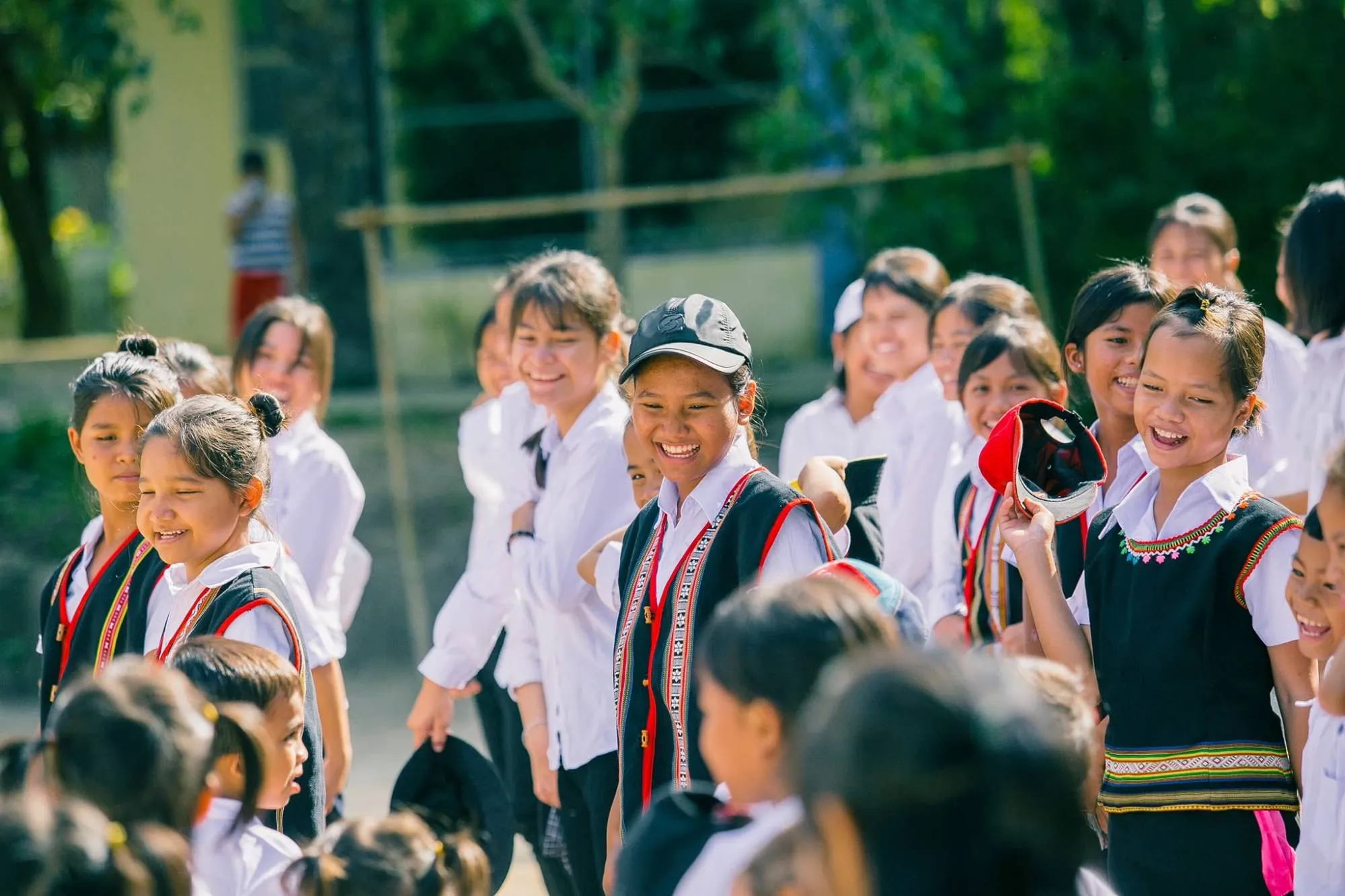 Students in woven vests laughing together in a schoolyard