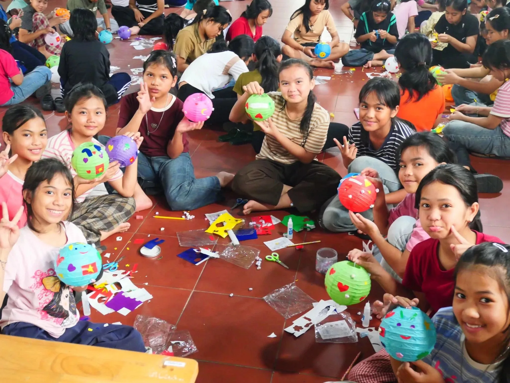 Children holding up the paper lanterns they decorated
