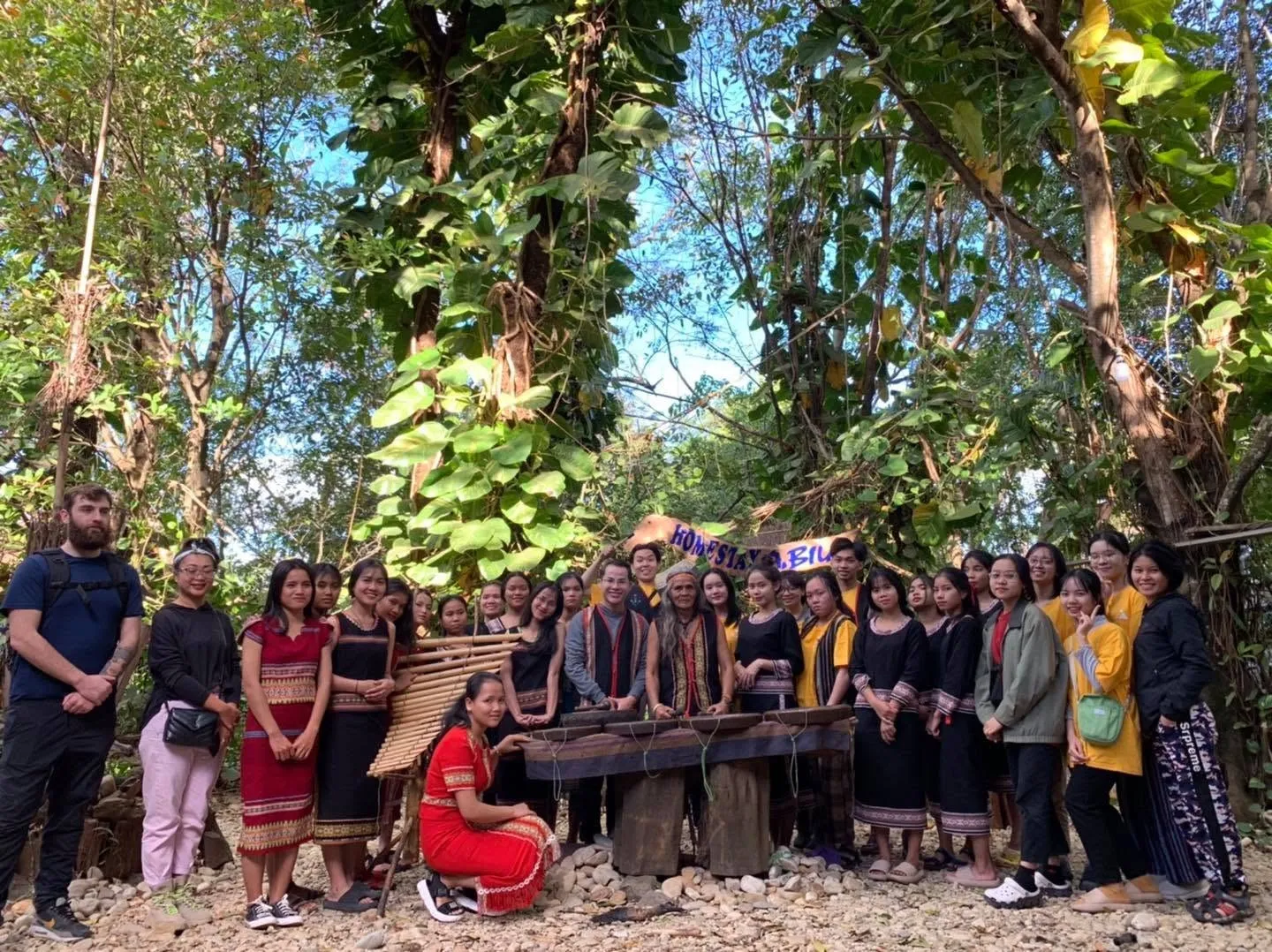 YETI students and facilitators with a village elder and his gongs in the forest in Kon Tum