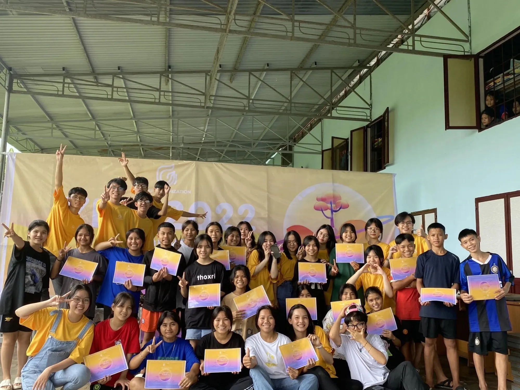 Students holding their certificates in front of the YETI 2022 banner